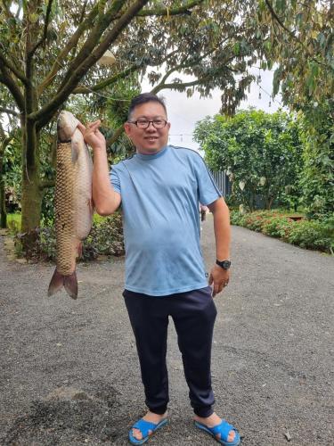 a man holding up a fish in the air at Homestay Vườn Trái Cây Nhiệt Đới VÔ ƯU GARDEN in Bao Loc