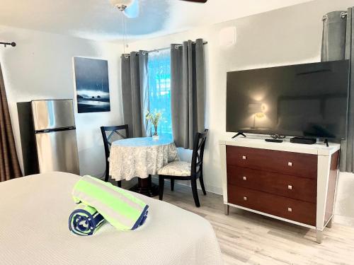 a bedroom with a large flat screen tv and a table at Organic Beach Retreat in Daytona Beach