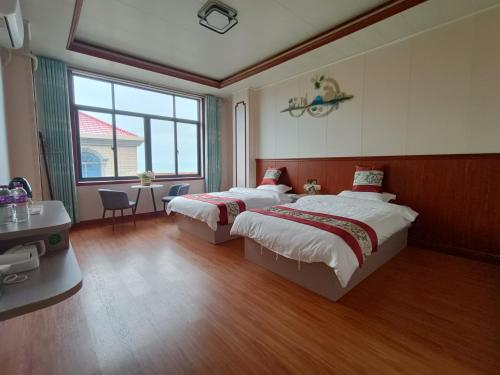 a bedroom with two beds and a table and a window at Meizhou Cloudy B&B in Putian
