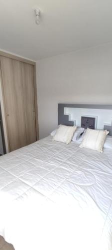 a large white bed with two pillows on it at Apartamento condominio Arica in Arica