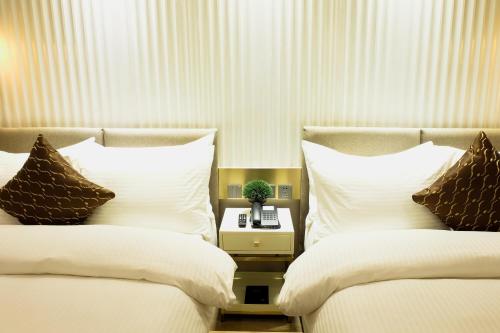 a bedroom with two beds with white sheets and brown pillows at Uma Hotel and Residences in Naga