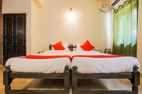 1 dormitorio con 2 camas y almohadas rojas en OYO La Petite Near Dabolim Airport en Chicolna