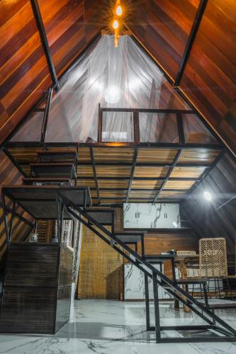 um sótão com um tecto de madeira e uma escada em Awandaru Village em Yogyakarta