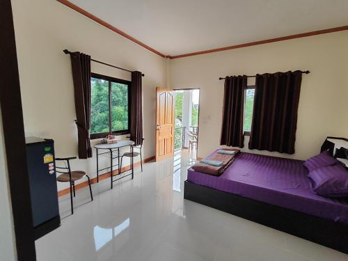 a bedroom with a purple bed and a table at Dowslom Place in Ban Phayun