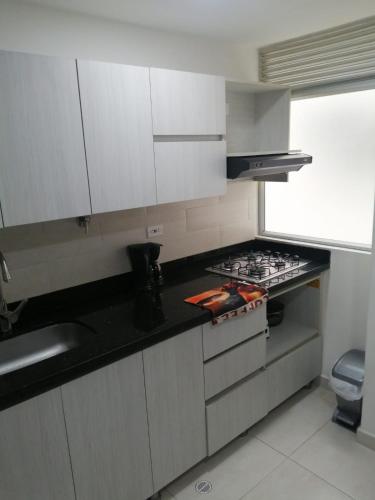 La cuisine est équipée de placards blancs et d'un four avec plaques de cuisson. dans l'établissement Apartamento Sabaneta sector Mayorca, à Sabaneta