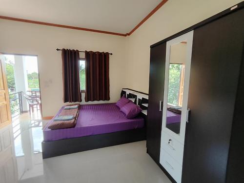 a bedroom with a purple bed in a room at Dowslom Place in Ban Phayun