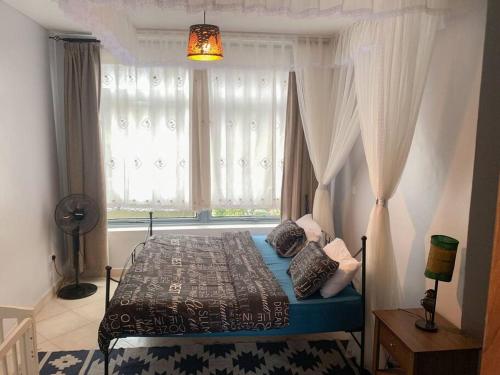 a bedroom with a bed in front of a window at Close to airport: 2 bedroom home, spacious & cosy in Entebbe