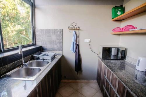 cocina con fregadero y ventana en Close to airport: 2 bedroom home, spacious & cosy en Entebbe