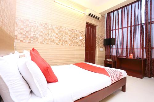 a bedroom with a bed with red and white pillows at Hotel Day Springs in Kottayam