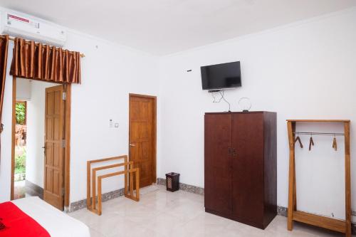 ein Schlafzimmer mit einem Bett und einem TV an der Wand in der Unterkunft RedDoorz At Grha Timoho Balai Kota Yogyakarta in Demangan