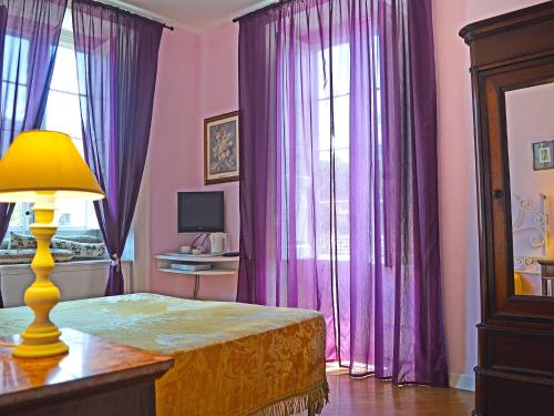a bedroom with purple curtains and a table with a lamp at The Secret Garden Relais in Piano di Sorrento