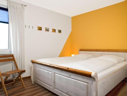 Bett in einem Zimmer mit gelber Wand in der Unterkunft Residenz am Yachthafen Hornhecht in Kirchdorf