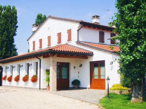 Casa blanca con techo rojo en Agriturismo Le Cipressine, en Meolo