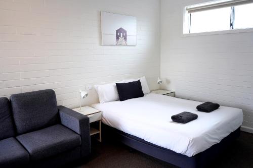 een slaapkamer met een bed en een stoel bij Guichen Bay Motel in Robe