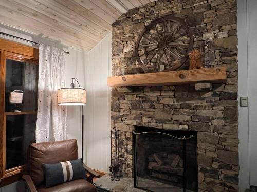 a stone fireplace with a wheel on top of it at Golden Acres Ranch Hot Tub+Gameroom+Creek & wifi in Highlands