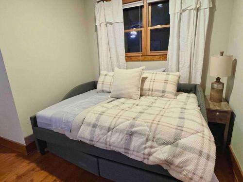 a bed with a plaid blanket and a window at Golden Acres Ranch Hot Tub+Gameroom+Creek & wifi in Highlands