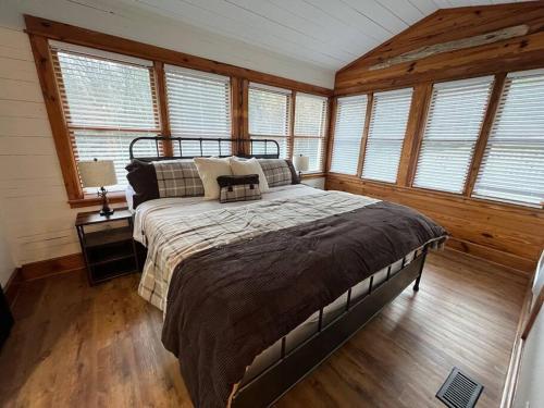 a bedroom with a large bed in a room with windows at Golden Acres Ranch Hot Tub+Gameroom+Creek & wifi in Highlands