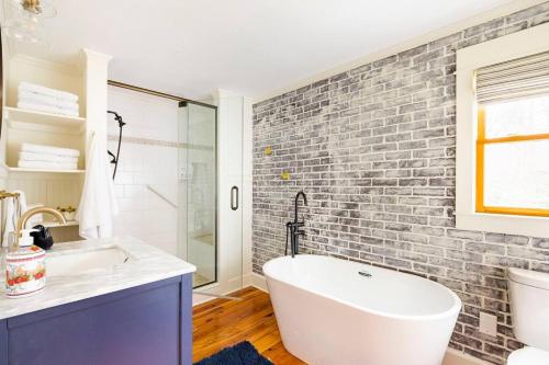 a bathroom with a white tub and a brick wall at Golden Acres Ranch Hot Tub+Gameroom+Creek & wifi in Highlands
