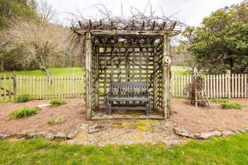 a bench in a garden with a wooden gazebo at Golden Acres Ranch Hot Tub+Gameroom+Creek & wifi in Highlands