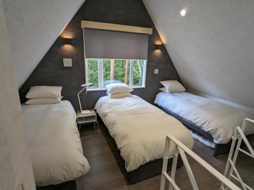 two beds in a room with a window at Summit Chalets in Hakuba