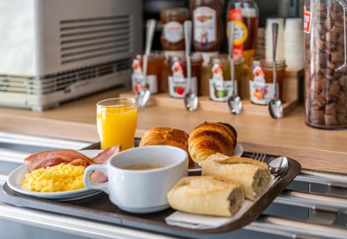 a tray with breakfast foods and a cup of orange juice at B&B HOTEL Saint Jean De Maurienne in Sainte-Marie-de-Cuines