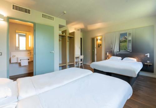 a hotel room with two beds and a bathroom at B&B HOTEL Saint Jean De Maurienne in Sainte-Marie-de-Cuines