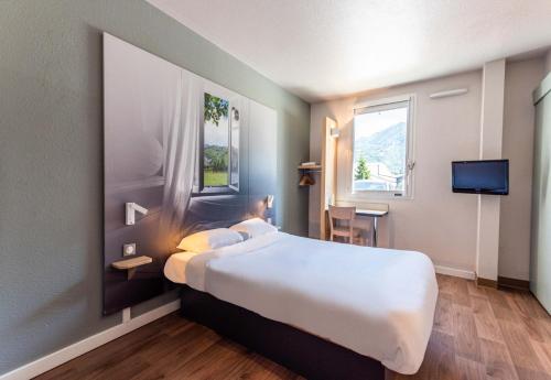 a hotel room with a large bed and a tv at B&B HOTEL Saint Jean De Maurienne in Sainte-Marie-de-Cuines