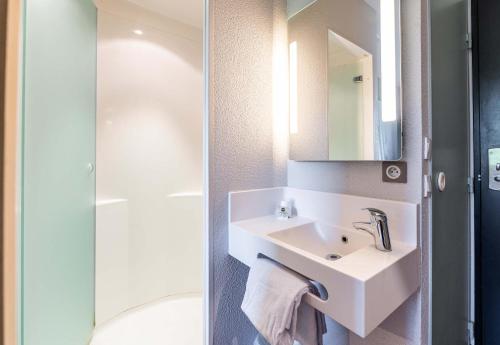 een witte badkamer met een wastafel en een douche bij B&B HOTEL Saint Jean De Maurienne in Sainte-Marie-de-Cuines