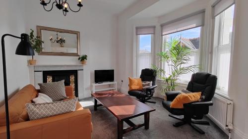 a living room with a couch and chairs and a fireplace at Fernhurst holiday apartments in Shanklin