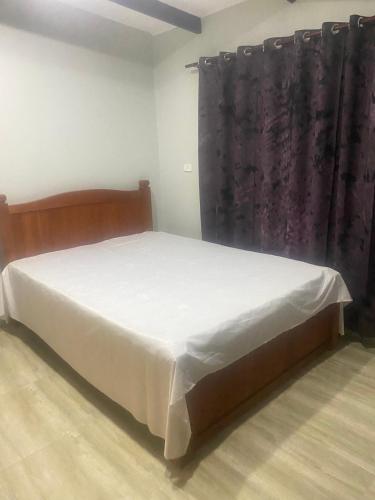 Hasmat Road في Nausori: غرفة نوم بسرير مع شراشف بيضاء وستارة