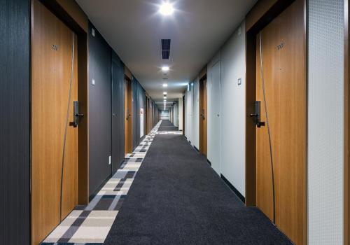 a hallway with wooden doors and a long corridor at Daiwa Roynet Hotel Kobe Sannomiya in Kobe