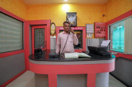 a man talking on a cell phone at a cash register at SPOT ON Hotel Ramgiri in Rāmtek
