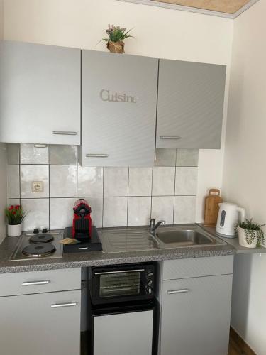 una cocina con armarios blancos y fregadero en Charmant studio, en Binche
