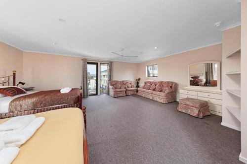 a hotel room with a bed and chairs and a mirror at Tuggeranong Short Stay #11C - Sleeps 8 in Canberra