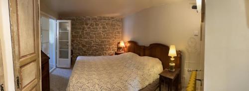 une chambre avec un lit et un mur en pierre dans l'établissement Gîte Maison provençale Coeur du Var (rez-de-chaussée), à Gonfaron