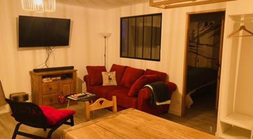a living room with a red couch and a tv at Appartement familial station de Peyragudes in Germ