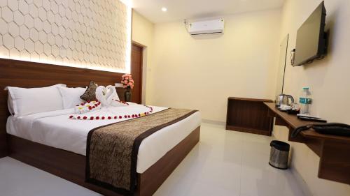 a hotel room with a bed and a television at Hotel Grand Square in Yercaud