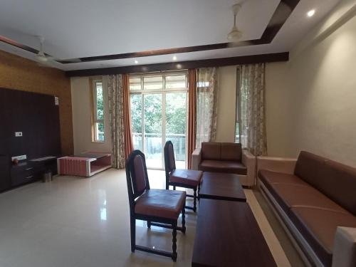 ein Wohnzimmer mit einem Sofa, einem Tisch und Stühlen in der Unterkunft oakwood mahabaleshwar in Mahabaleshwar