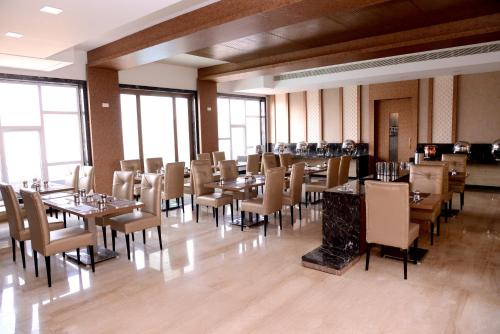 un comedor con mesas, sillas y ventanas en Hotel Regency Inn, en Erode