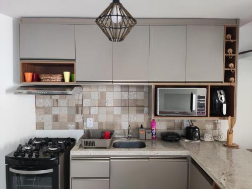 a kitchen with white cabinets and a sink and a stove at Casa de Veraneio na Praia do Francês in Marechal Deodoro