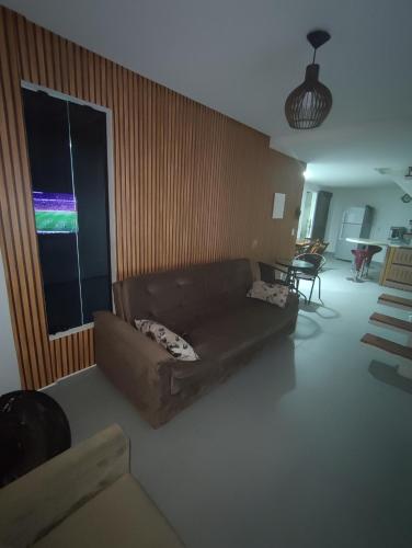 a living room with a brown couch and a window at Casa de Veraneio na Praia do Francês in Marechal Deodoro