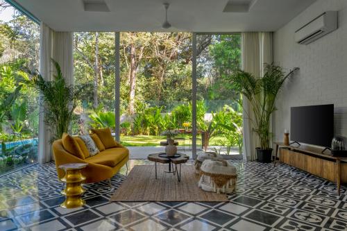 a living room with a yellow couch and a tv at La Macedo, Luxury 3 BHK Villas in Assagao, with Private Pool, Garden, Terrace, Parking, Security in Mapusa