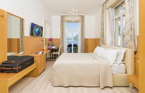 a bedroom with a bed and a desk and a window at Hotel Victoria in Lugano