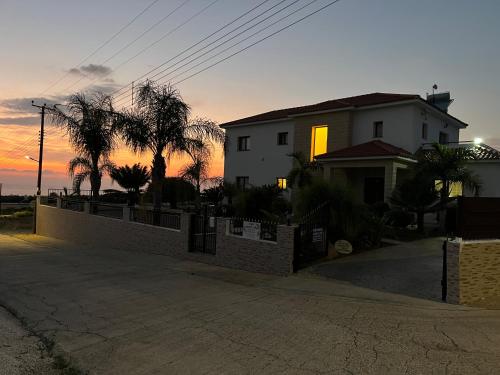 a house with a fence in front of a sunset at Nayia Paradise Villa! Best Villa in Cyprus in Paphos City