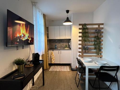 a living room with a table and a kitchen with a fireplace at Le petit Sartrouville à 20 min de Paris en RER A in Sartrouville