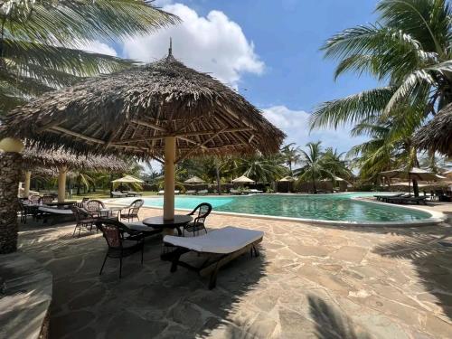 a resort with a pool with chairs and an umbrella at Beach front villa in Malindi in Malindi