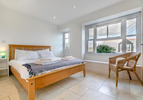 a bedroom with a bed and a chair and a window at Gartree Cottage in Fowey