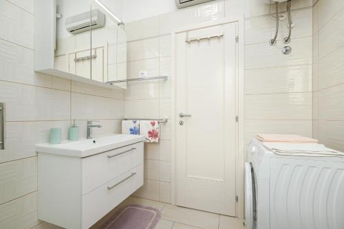 a white bathroom with a sink and a washing machine at Valnea - apartment for five people in the center of Poreč in Poreč