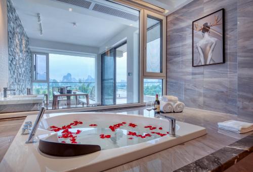 uma casa de banho com uma banheira com flores vermelhas em Guilin Yangshuo Waterhouse River View Villa em Yangshuo