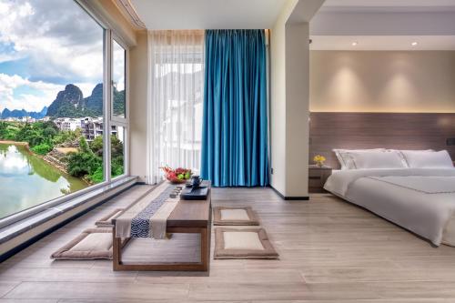 a bedroom with a bed and a large window at Guilin Yangshuo Waterhouse River View Villa in Yangshuo